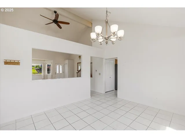 a view of livingroom with chandelier fan and kitchen view