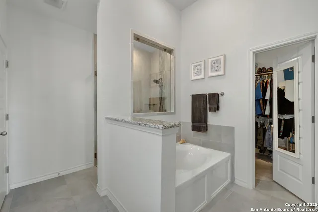 a spacious en suite bathroom with a granite countertop sink and a mirror