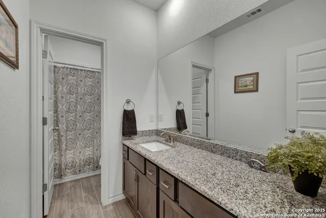 a bathroom with a granite countertop sink a mirror and shower