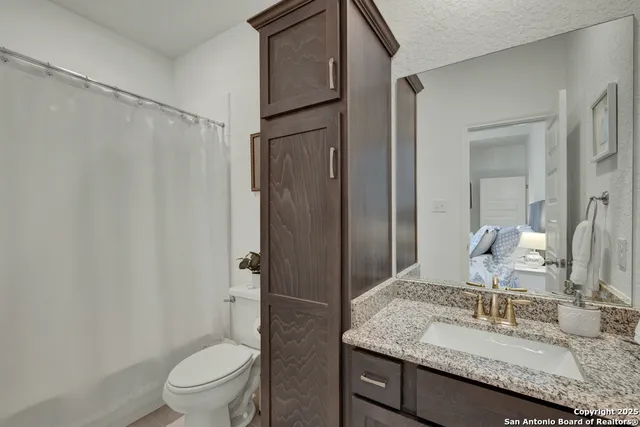 a bathroom with a granite countertop sink toilet and shower