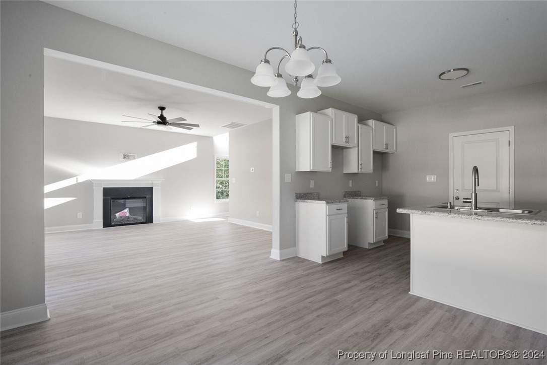 57 3rd Street Parkton, NC 28371 - Photo 8 of 24 a large kitchen with cabinets a sink dishwasher a dining table and chairs with wooden floor