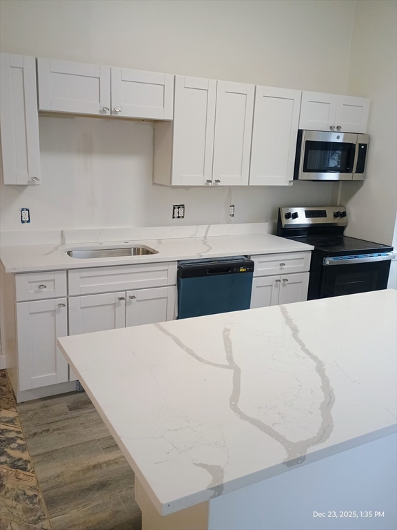 348 Main Street, Unit R Douglas, MA 01516 - Photo 2 of 9 a kitchen with stainless steel appliances a sink dishwasher a stove top oven a refrigerator with white cabinets and wooden floor
