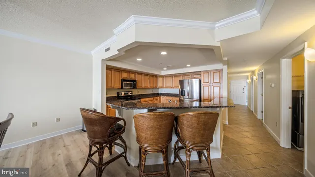 a kitchen with stainless steel appliances granite countertop a stove top oven a sink dishwasher a refrigerator and cabinets with wooden floor