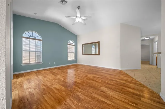 a view of a livingroom with wooden floor and kitchen view