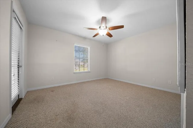 a view of an empty room with chandelier fan and a window