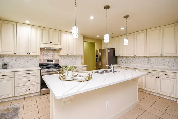 a kitchen with a stove a sink a center island and cabinets