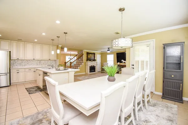 a view of a kitchen with kitchen island a stove a refrigerator a sink dishwasher with a dining table and chairs