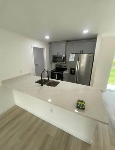 a view of kitchen with stainless steel appliances granite countertop refrigerator sink and stove