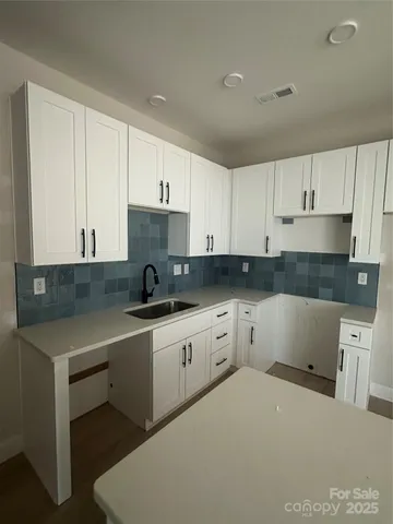 a kitchen with white cabinets sink and stove