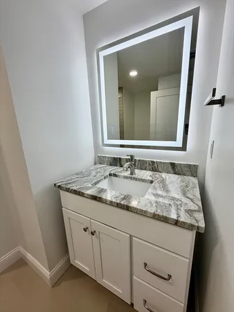 a bathroom with a granite countertop sink and a mirror