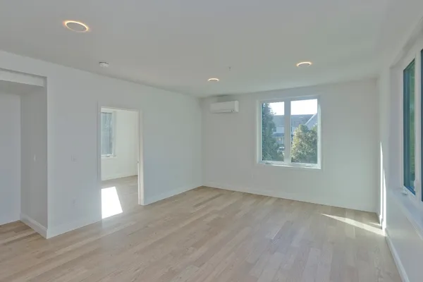 an empty room with wooden floor and windows