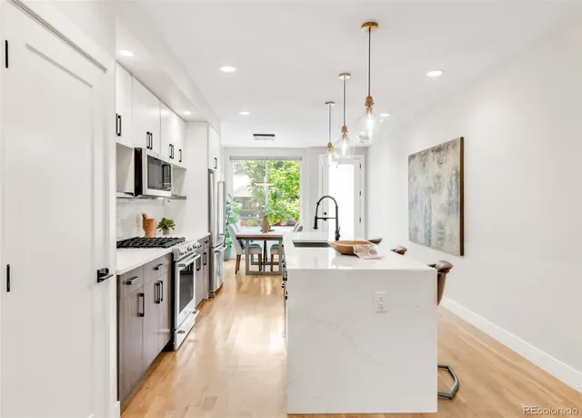 a kitchen with stainless steel appliances kitchen island a stove a sink a oven a dining table and chairs