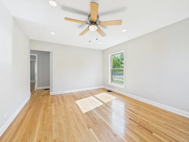 a view of an empty room with window and wooden floor