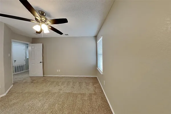 an empty room with closet and a ceiling fan