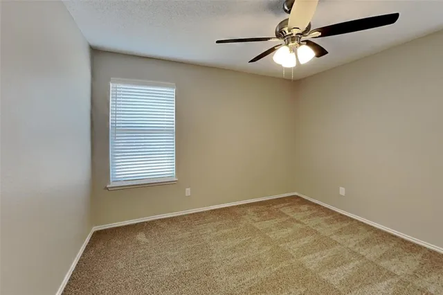 an empty room with a window and a fan