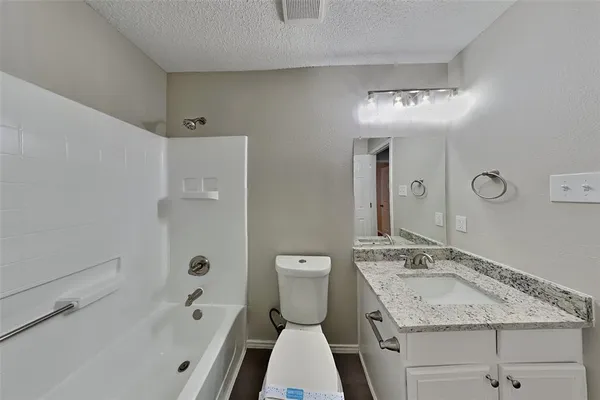 a bathroom with a granite countertop sink a toilet a mirror and shower