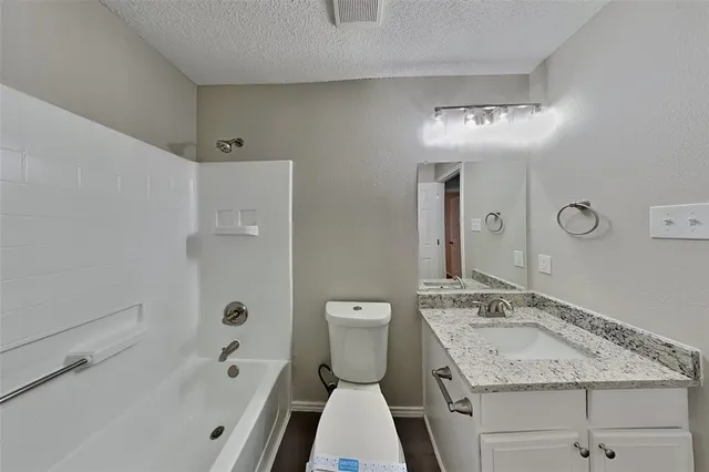 a bathroom with a granite countertop sink a toilet a mirror and shower