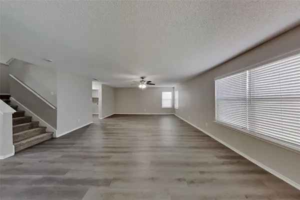 a view of an empty room with a window and wooden floor