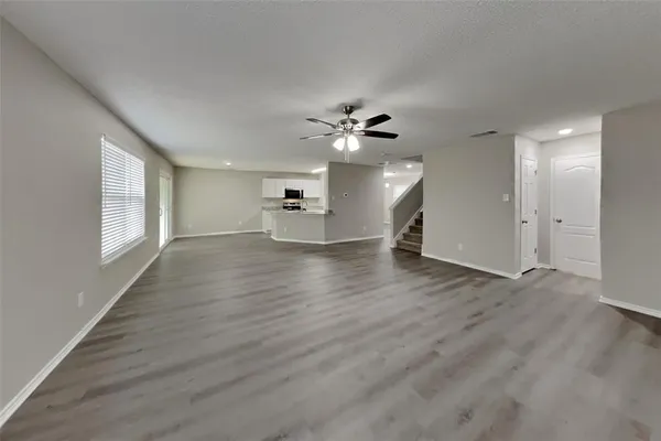 a view of an empty room with a window and wooden floor