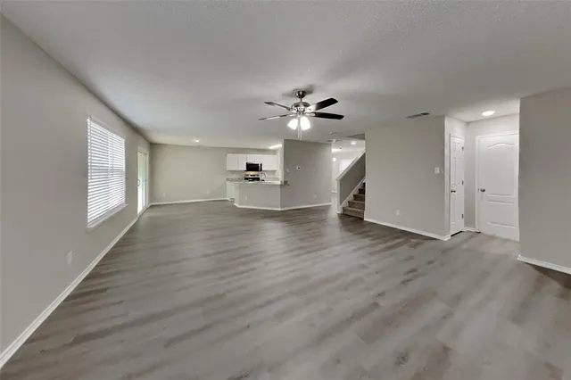 a view of an empty room with a window and wooden floor