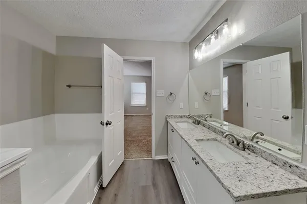 a bathroom with a granite countertop sink mirror and a bath tub