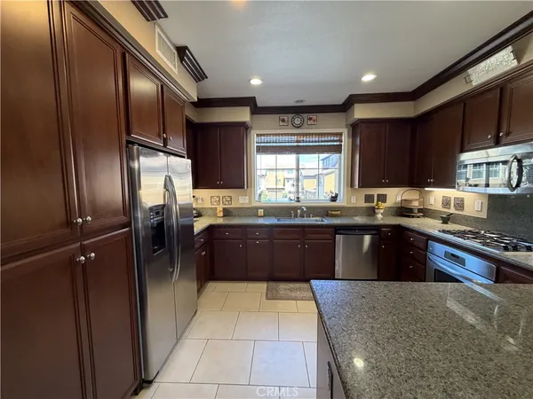 a large kitchen with granite countertop a refrigerator and wooden cabinets