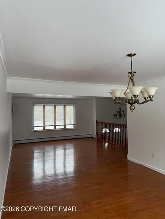 a view of a room with wooden floor fire place and windows