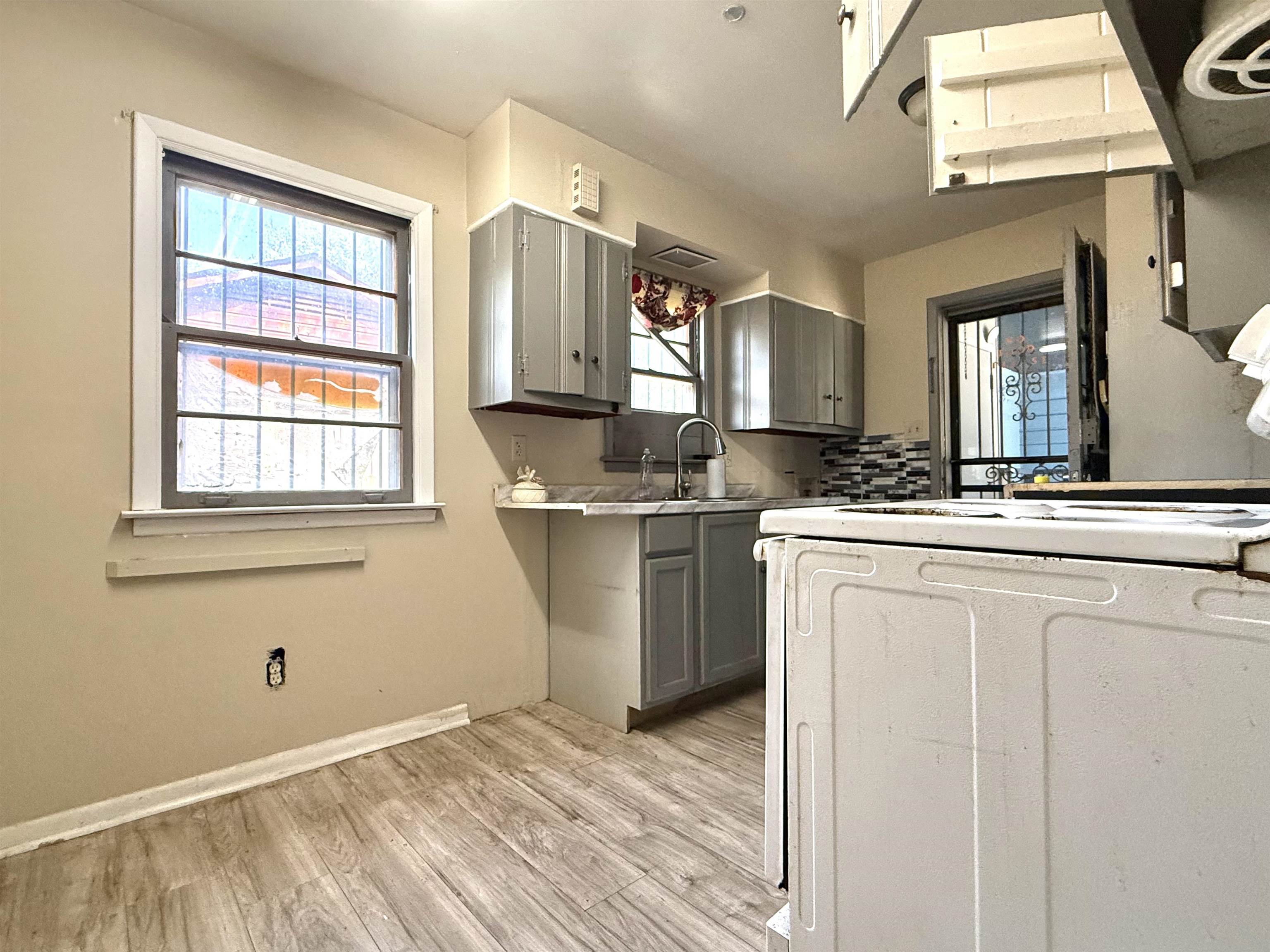 2930 Getwell Road Memphis, TN 38118 - Photo 16 of 25 Kitchen featuring wood-finish flooring, gray cabinetry, a mosaic tile backsplash, and a stainless steel sink with a gooseneck faucet