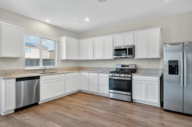 a kitchen with stainless steel appliances granite countertop a stove a sink and a microwave