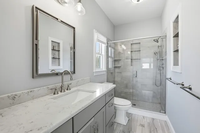 a bathroom with a granite countertop sink toilet a large mirror and shower