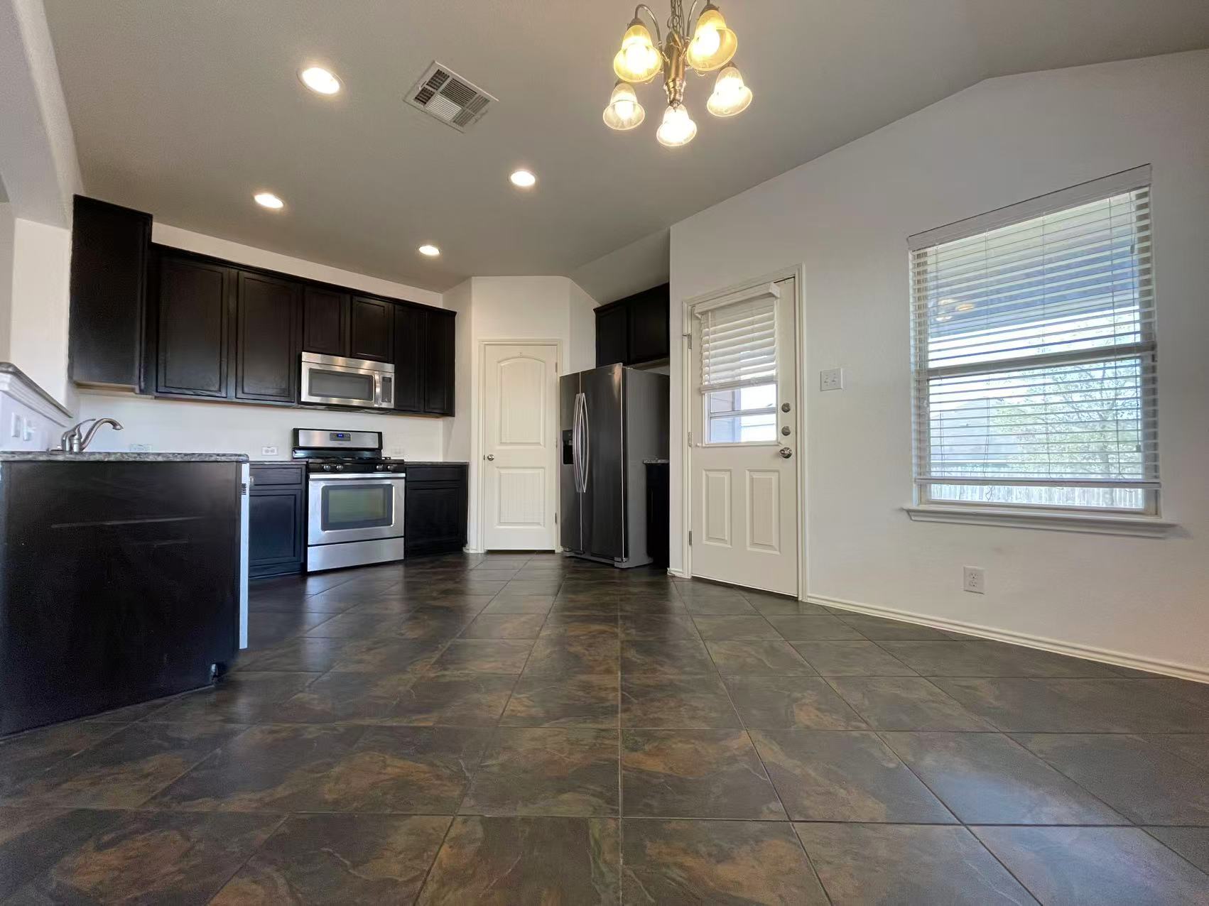 457 Dragon Ridge Road Buda, TX 78610 - Photo 10 of 29 Kitchen with stainless steel appliances, hanging lights, dark cabinets, and light stone countertops