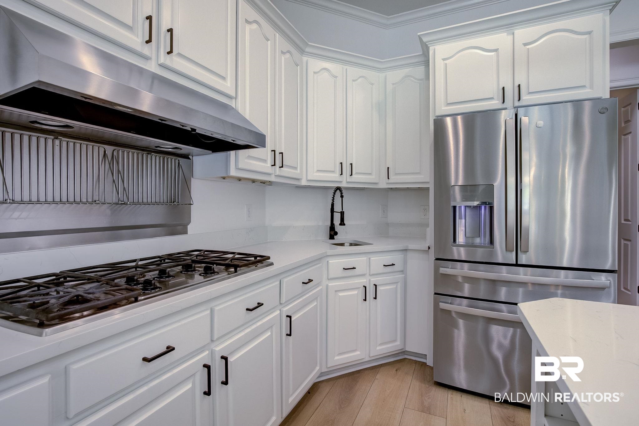 105 High Pines Ridge Fairhope, AL 36532 - Photo 32 of 97 Kitchen with appliances with stainless steel finishes, a sink, under cabinet range hood, white cabinetry, and light wood-type flooring