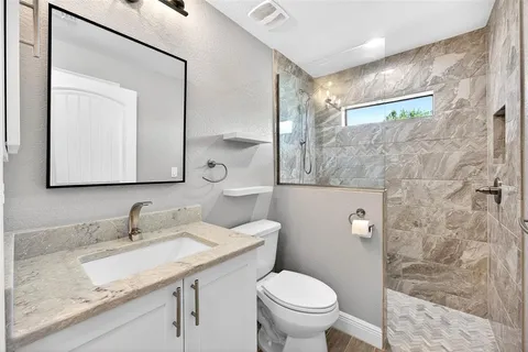 a bathroom with a granite countertop sink a toilet and a mirror