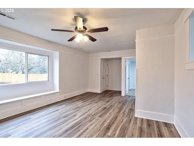 a view of an empty room with wooden floor and a window