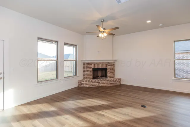 a kitchen with stainless steel appliances granite countertop a refrigerator a sink dishwasher a stove and white cabinets with wooden floor