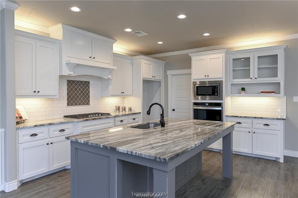 a kitchen with granite countertop a stove a sink dishwasher a refrigerator with white cabinets and wooden floor