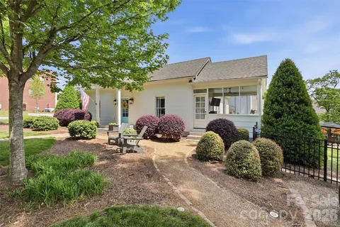 a backyard of a house with table and chairs plants and large tree