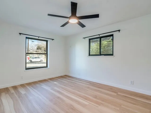a view of an empty room with window and wooden floor