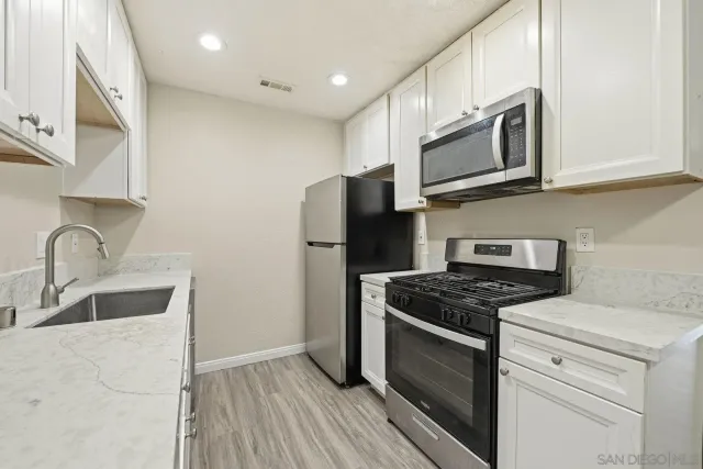 a kitchen with stainless steel appliances granite countertop white cabinets a stove top oven a sink and dishwasher