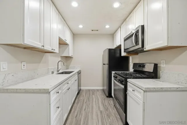 a kitchen with granite countertop a sink stove and refrigerator