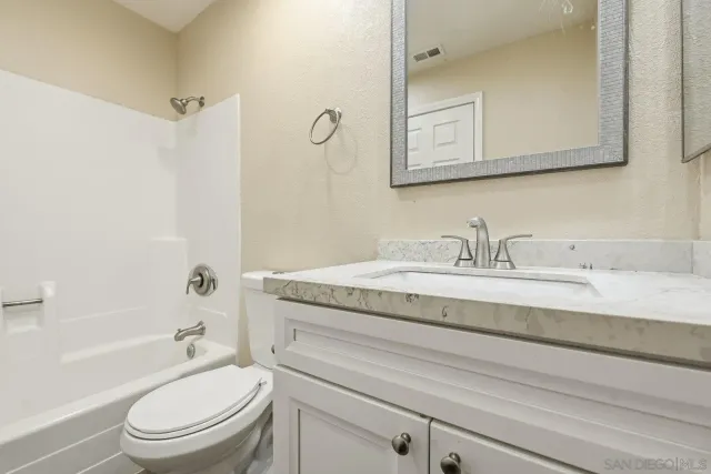 a bathroom with a granite countertop toilet a sink and a bathtub