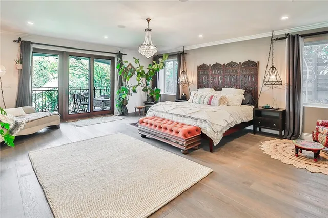 a bedroom with a bed chandelier and a large window