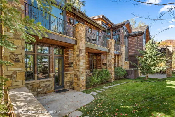 a living room with furniture large windows a rug and a chandelier