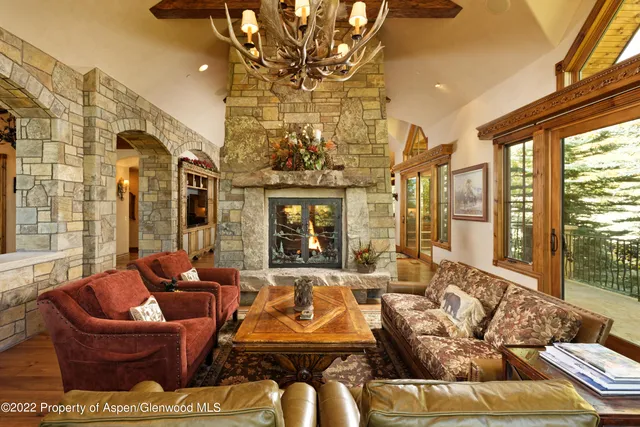 a living room with furniture large windows a rug and a chandelier