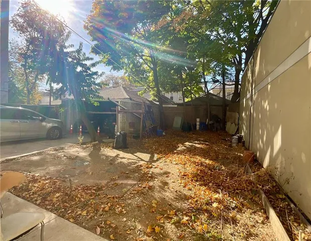 a view of a yard with plants and large trees