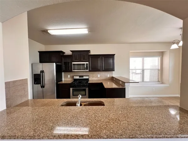 a kitchen with kitchen island granite countertop a refrigerator stove top oven and sink