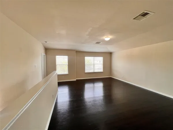 a view of an empty room with a window and wooden floor