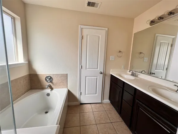 a bathroom with a tub sink and mirror
