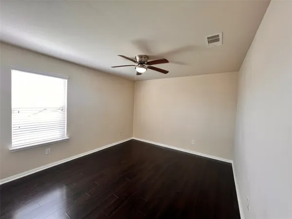 an empty room with a window and a ceiling fan