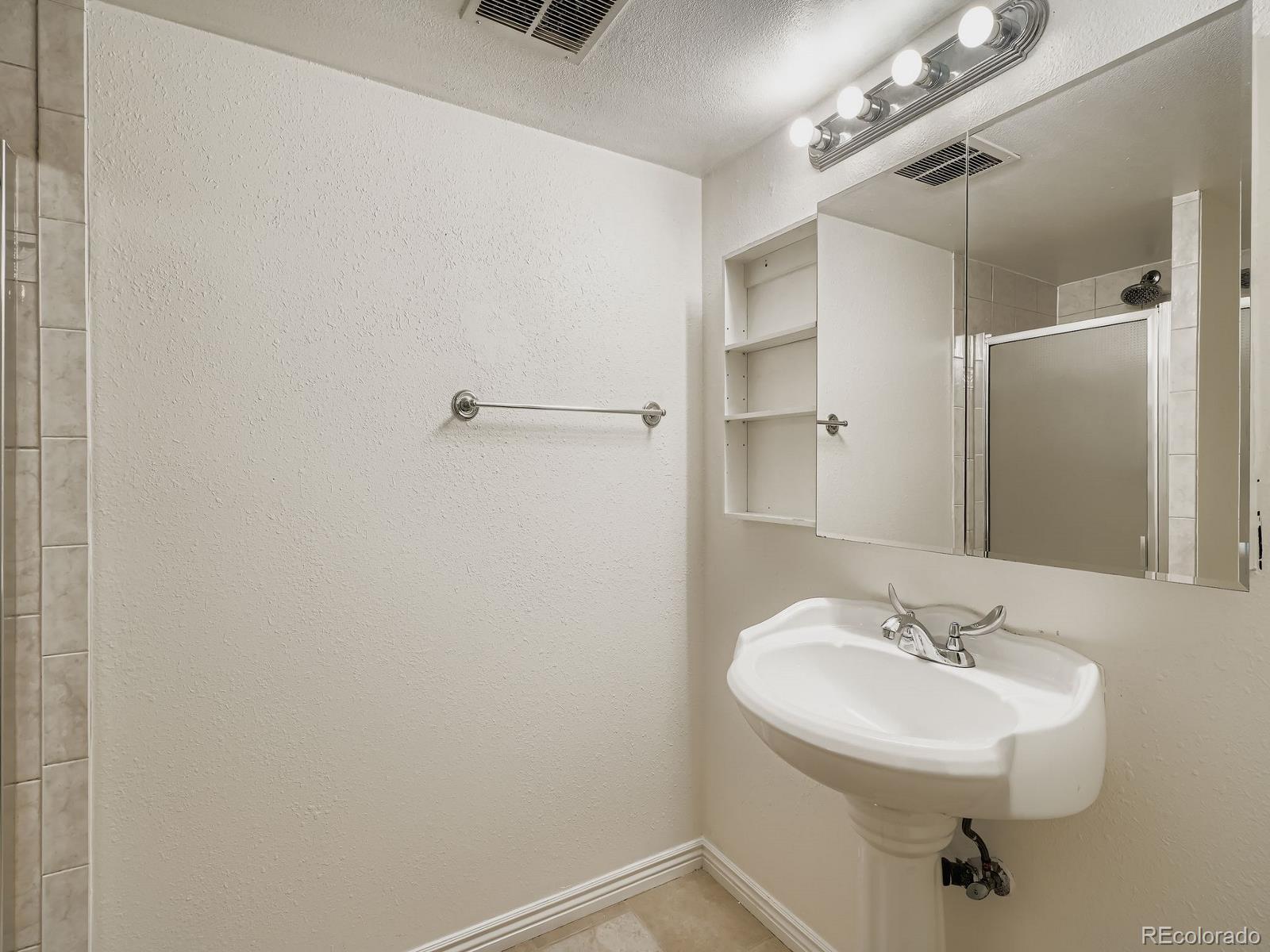3420 South Locust Street, Unit D Denver, CO 80222 - Photo 12 of 16 a bathroom with a sink a mirror and a shower